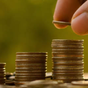 IT Budget represented by a man stacking coins atop one another.