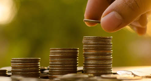 IT Budget represented by a man stacking coins atop one another.